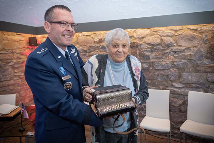 Air Force Lt. Gen. Scott A. Kindsvater, deputy chairman of the NATO Military Committee, hands over an accordion to Christel Nierhoff in Schleiden, Germany